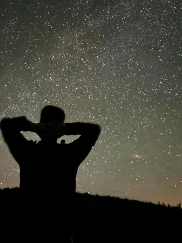 a man looking up at the stars in the sky at A Barreira -Lar da cima- in Folgoso