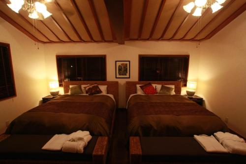 a bedroom with two beds and two windows and lights at Cottage Hakuraku in Onna