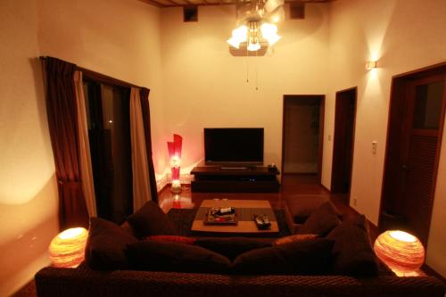 a living room with a couch and a tv at Cottage Hakuraku in Onna