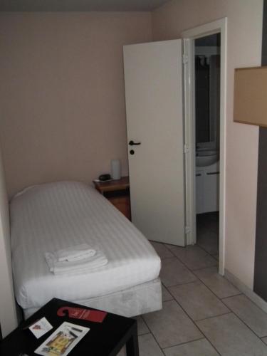 a small bedroom with a bed and a door at Condo Gardens Brussels in Brussels
