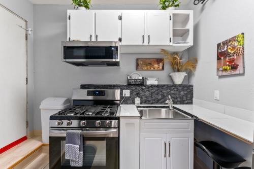 a kitchen with white cabinets and a stove and a sink at Stylish Studio Suite Near Downtown in Anchorage