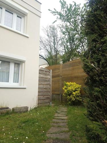 une clôture en bois à côté d'une maison blanche dans l'établissement Logement indépendant, proche gare, à Aubergenville