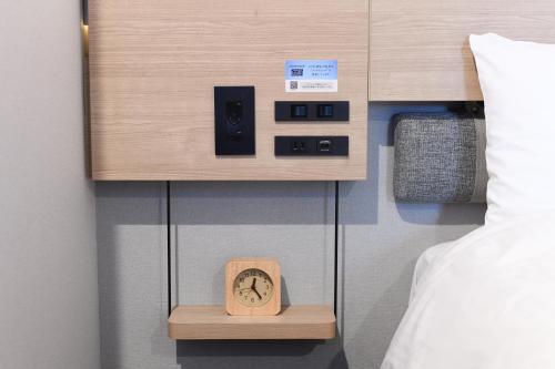 a clock on a shelf next to a bed at Washington R&B Hotel Otsuka Eki Kitaguchi in Tokyo