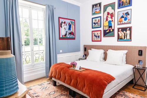 une chambre avec un lit avec des tableaux sur les murs dans l'établissement Domaine du Chesney, à Pressagny l'Orgueilleux