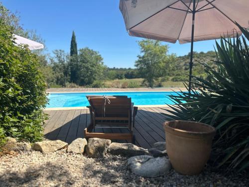 - une terrasse avec une chaise et un parasol à côté de la piscine dans l'établissement BERGERIE rénovée avec piscine chauffée et terrain clôturé, à Vallérargues