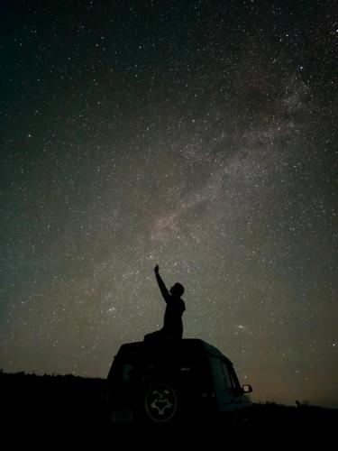 a person standing on the top of a truck looking at the stars at A Barreira -Lar da cima- in Folgoso