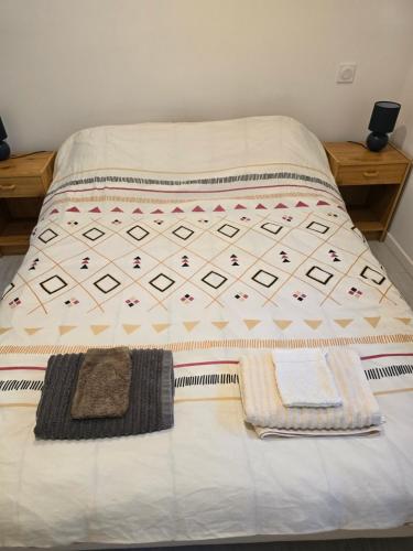a bed with two blankets and two towels on it at Les Rochettes, joli appartement, tout neuf, calme et paisible in Saint-Gervais-dʼAuvergne