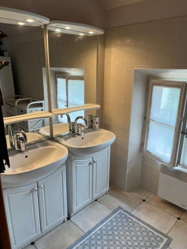 une salle de bain avec deux lavabos et un grand miroir dans l'établissement Maison Gometz, à Gometz-le-Châtel