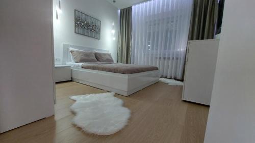 a white bedroom with a bed and a white rug at MINA modern & cozy apartment main city square GTC Skopje in Skopje