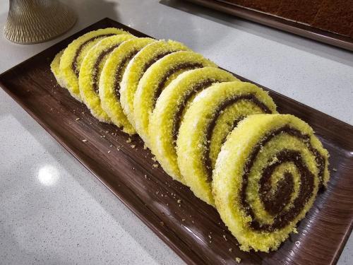 a cake with yellow frosting on a wooden plate at Hotel Nanni Garnì in Rimini