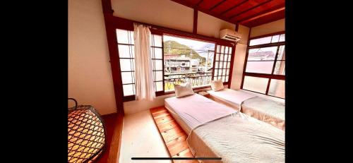 a bedroom with two beds and a window with a view at 三丁庵ゲストハウス 水質AAビーチまで徒歩15分ペリーロードまで徒歩5分最高なロケーション 下田を遊び尽くせるゲストハウス 無料駐車場もありますJapanese old style guest house that 2 minutes walk to Perry Road 15ninutes walk to Nabeta beach in Harada
