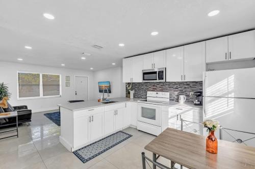 a kitchen with white cabinets and a table in a room at 2 Bdrm Modern House Mins From Beach & Casino Hb1 in Hallandale Beach