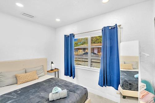 Un dormitorio con una cama y una ventana con cortinas azules. en Boutique One Bdrm Close To Aventura Mall & Beach, en Hallandale Beach