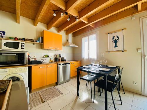 une cuisine avec une table et une cuisine avec des armoires orange dans l'établissement Casa Mandarine, à Angers
