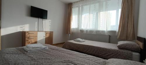 a hotel room with two beds and a window at M Family Apartment in Odorheiu Secuiesc