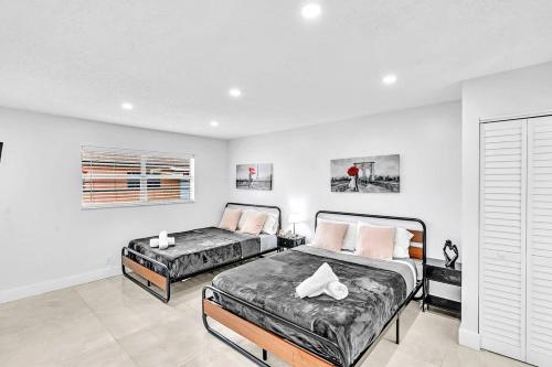 two beds in a bedroom with white walls at Beach And Hard Rock Hollywood Vacation House Ha02 in Hollywood