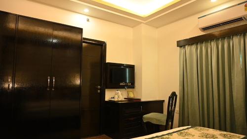 a hotel room with a bed and a tv and a desk at The Vaishnavi in Deoghar