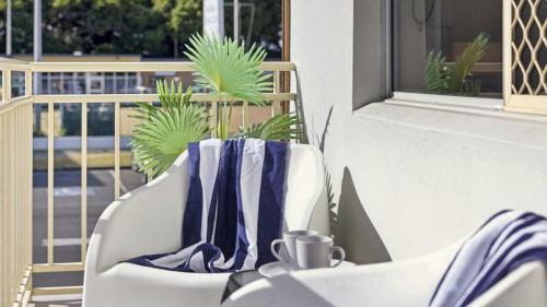 a white chair with a blue napkin and a cup on it at Ocean Echoes Coffs Harbour- Short walk to the beach, Cafes and clubs! in Coffs Harbour