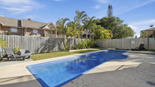 a swimming pool in a yard next to a fence at Ocean Echoes Coffs Harbour- Short walk to the beach, Cafes and clubs! in Coffs Harbour