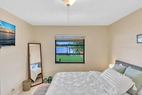 a bedroom with a bed and a mirror and a window at Beautiful Cozy Lakefront HomeCasinoAirportBeach in Fort Lauderdale