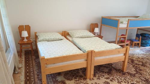two twin beds in a room with two tables at Tkalcovna U Zlatého potoka in Dobřany