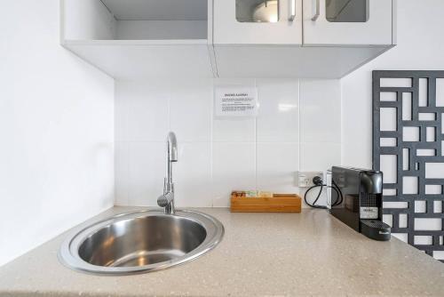 eine Küchentheke mit einer Edelstahlspüle in der Unterkunft 'McLeod Corner' Resort-style Adjacent Apartments in Cairns