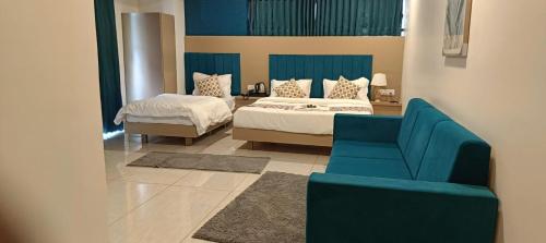 a bedroom with two beds and a blue couch at Hotel Royal Square in Gandhinagar