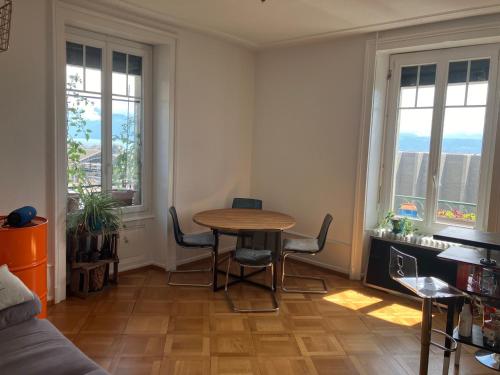 a living room with a table and chairs and windows at Laus-Angeles in Lausanne