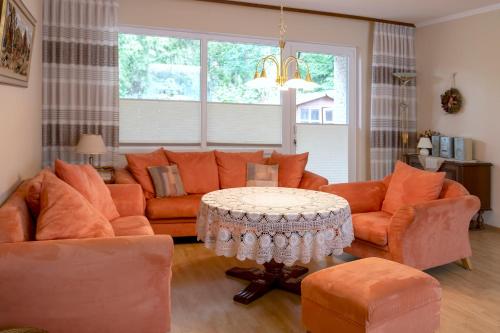 a living room with orange furniture and a table at Pension am Hardausee in Suderburg