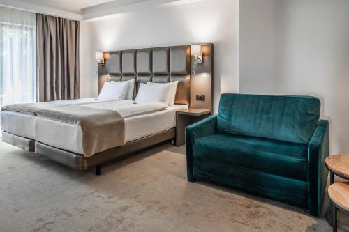 a bedroom with a bed and a green chair at Charm Boutique Hotel in Satu Mare