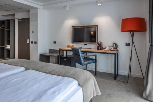 a bedroom with a desk with a television and a chair at Charm Boutique Hotel in Satu Mare
