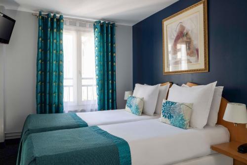 a bedroom with a large bed with blue walls at Grand Hotel Du Calvados in Paris