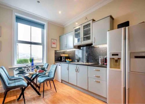 a kitchen with white appliances and a table with chairs at Jack's House in Tywyn