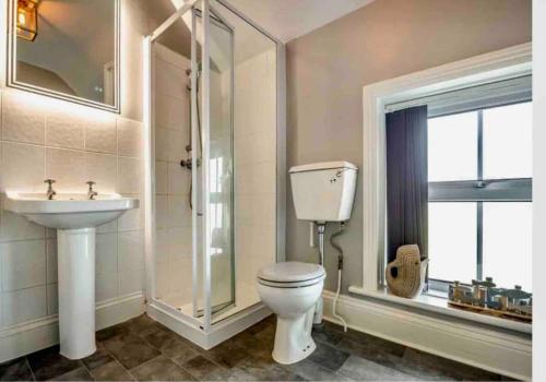 a bathroom with a toilet and a sink and a window at Jack's House in Tywyn