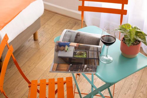 a table with a glass of red wine on it at Grand Hotel Du Calvados in Paris