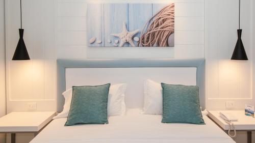 a bedroom with a white bed with two green pillows at Mangia's Pollina Resort in Cefalù