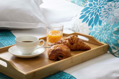 a tray with a cup of coffee and pastries on a bed at Grand Hotel du Calvados - Opera in Paris