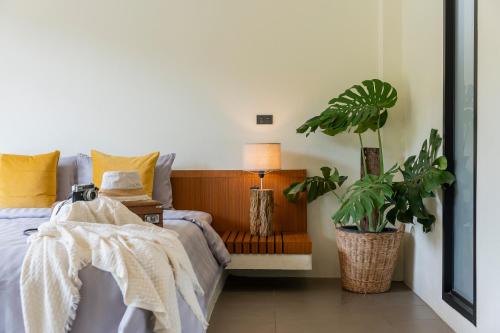 a bedroom with a bed and a lamp and a plant at Sirin Farm Chiang Rai in Ban San Ton Ko (1)