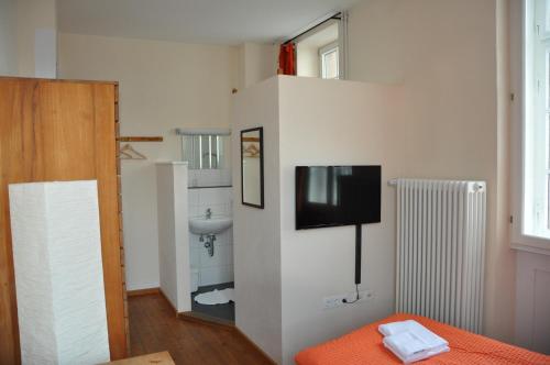 Zimmer mit einem TV an einer Wand und einem Waschbecken in der Unterkunft Gästehaus stuttgART36 in Maulbronn