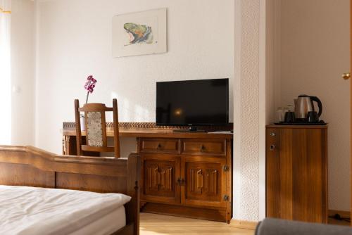 a bedroom with a television on a wooden dresser at Gosti&scaron;če Pri Dveh Petelinih in Bled