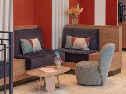 a living room with two couches and a table and a chair at Hotel Le Mareuil in Paris