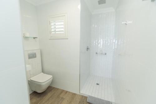 a white bathroom with a toilet and a shower at Luxury On The Beach in Summerstrand