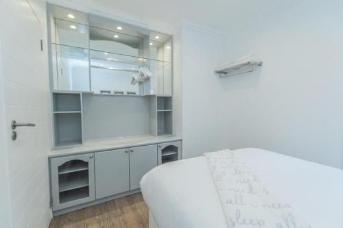 a white bedroom with a bed and a white cabinet at Luxury On The Beach in Summerstrand