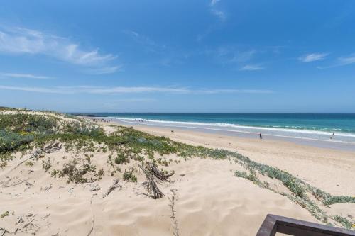 a sandy beach with people in the ocean at Luxury On The Beach in Summerstrand