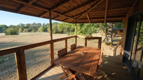 a porch with a wooden table and chairs on it at Les Cabanes de Lara in Ménesplet