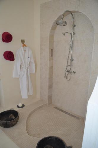 a bathroom with a shower with a white robe on a wall at Dar Salama in Bizerte