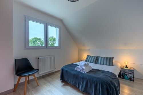 a bedroom with a bed and a chair and a window at L'Envolée de Charme - Maison à 10m de Vannes in Theix