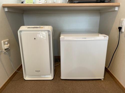 two white refrigerators sitting on the floor under a shelf at Family Stay Tsukuba Room in Tsukuba