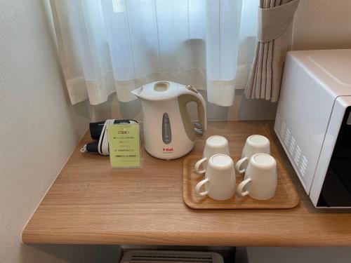 a counter with a tea kettle and two mugs on it at Family Stay Tsukuba Room in Tsukuba