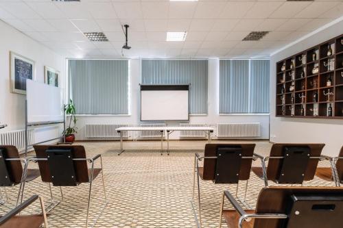 an empty room with chairs and a white screen at Hotel Marttel in Karlovy Vary
